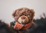 Adorable close-up of a plush teddy bear wearing a colorful scarf, perfect for cozy themed designs.
